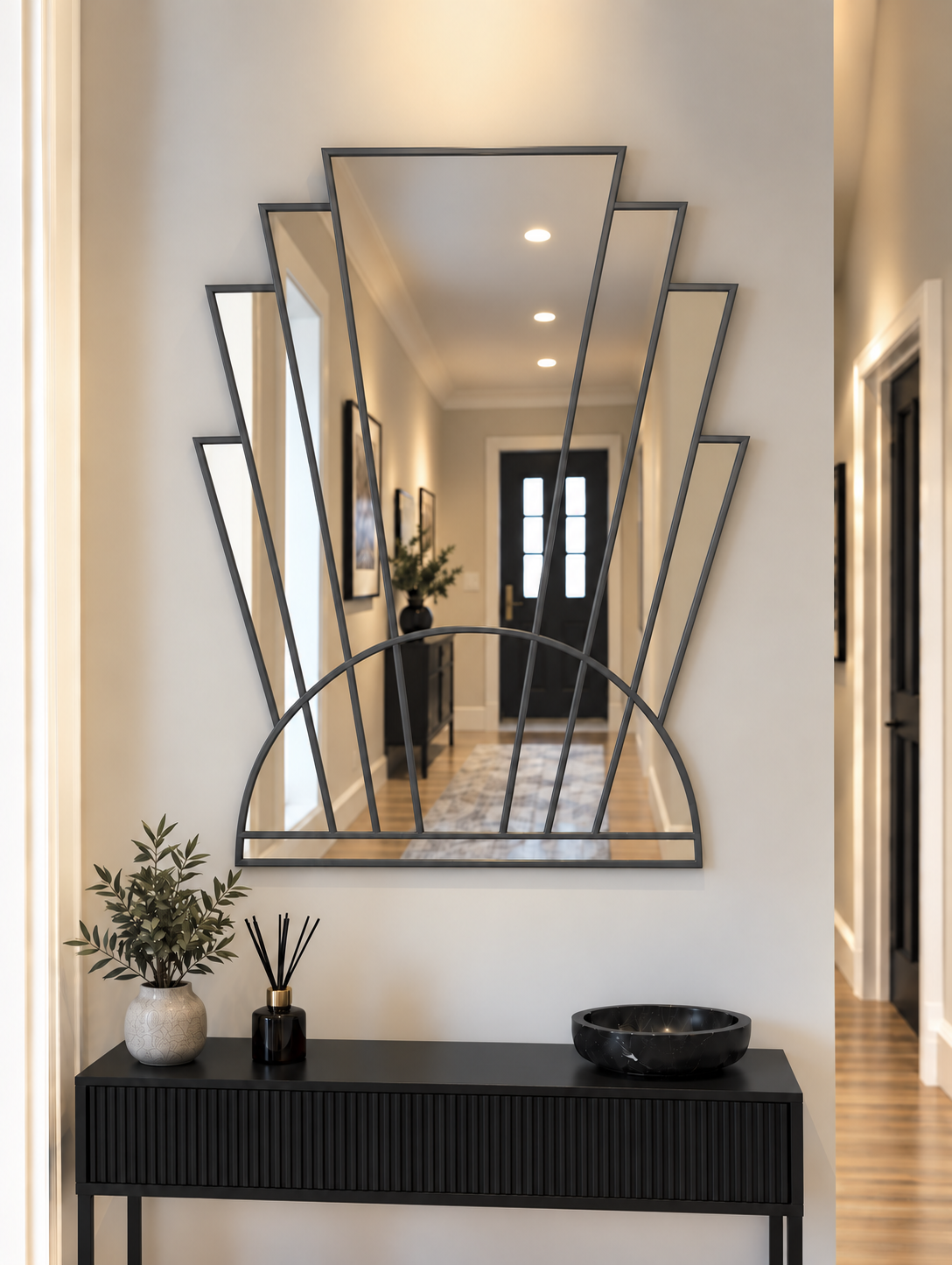 An Art Deco style wall mirror with an antique metal frame, featuring vertical mirror panels and a semi-circular arch base, mounted on a white wall.