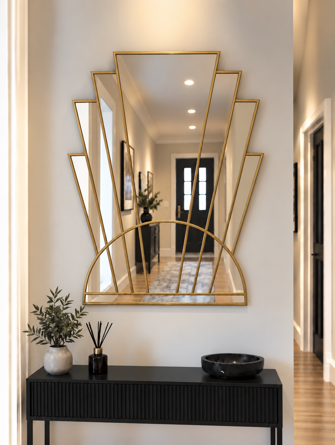 An Art Deco style wall mirror with a brass metal frame, featuring vertical mirror panels and a semi-circular arch base, mounted on a white wall.