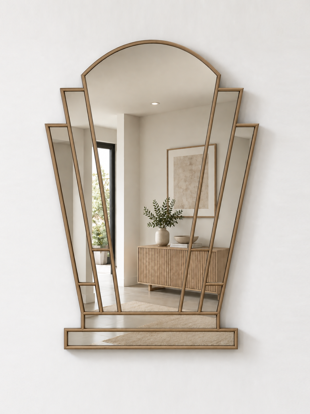 A gold-framed geometric wall mirror with an arched top and multiple angled panels, mounted on a white wall.