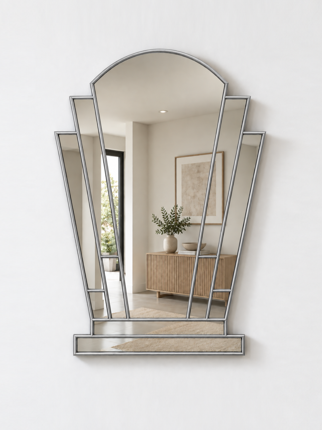 A silver-framed geometric wall mirror with an arched top and multiple angled panels, mounted on a white wall.