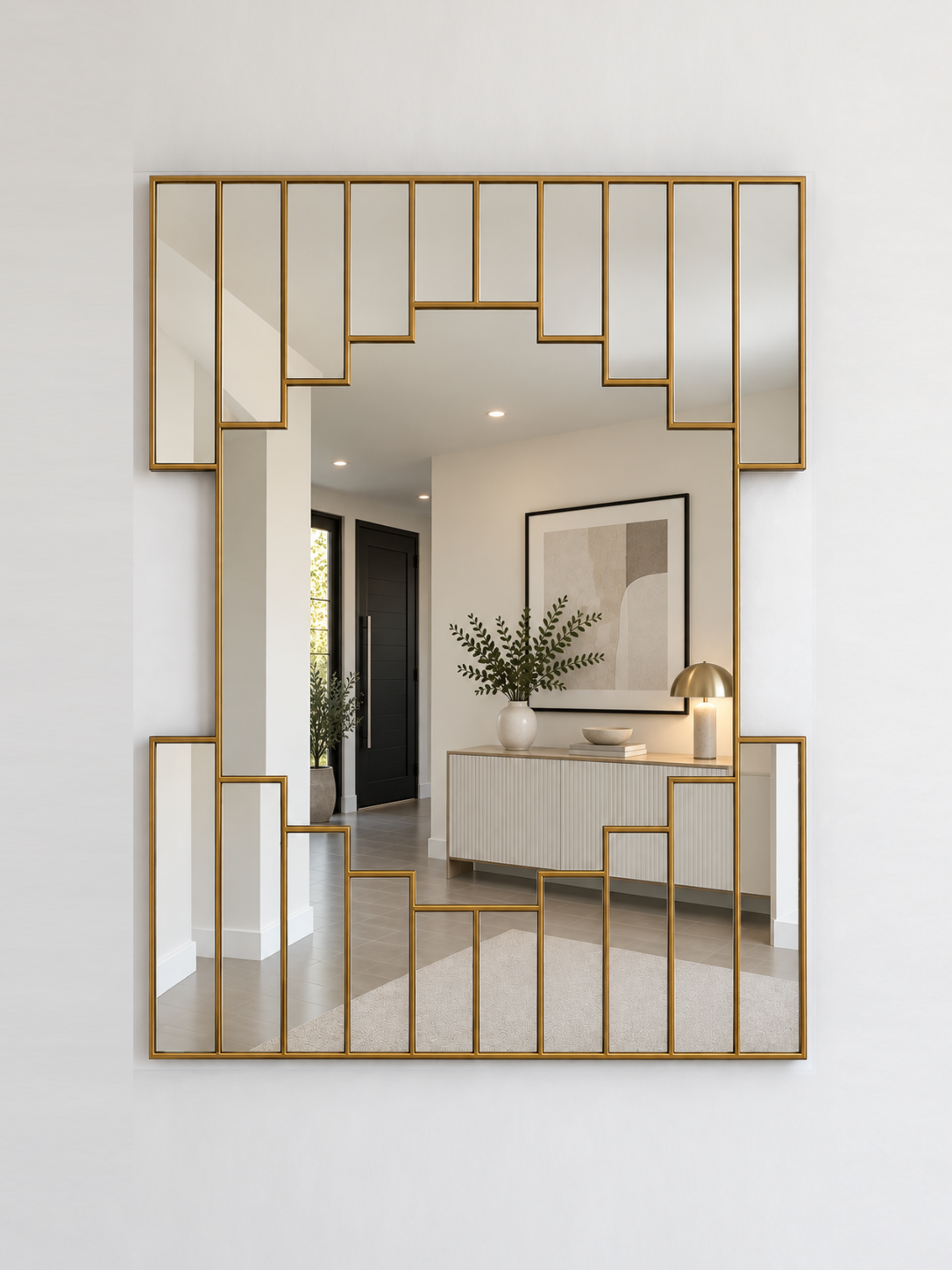 A large rectangular wall mirror with a brass geometric metal frame, mounted on a white wall. 