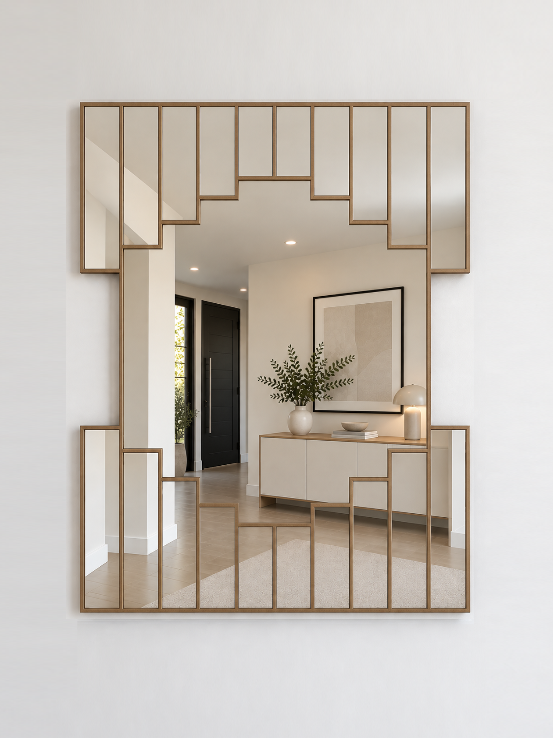 A large rectangular wall mirror with a gold geometric metal frame, mounted on a white wall. 