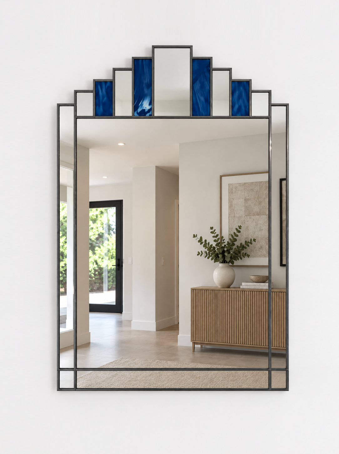 A large rectangular wall mirror with a antique metal frame and stepped top border featuring alternating blue and mirror panels