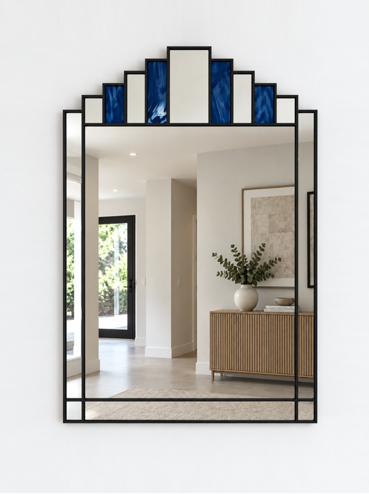 A large rectangular wall mirror with a black metal frame and stepped top border featuring alternating blue and mirror panels