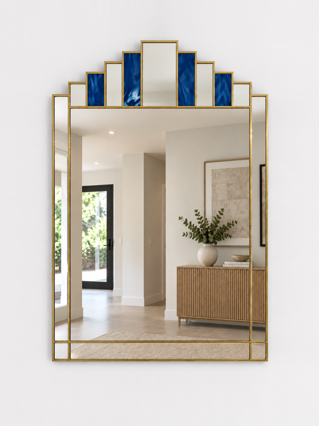 A large rectangular wall mirror with a brass metal frame and stepped top border featuring alternating blue and mirror panels