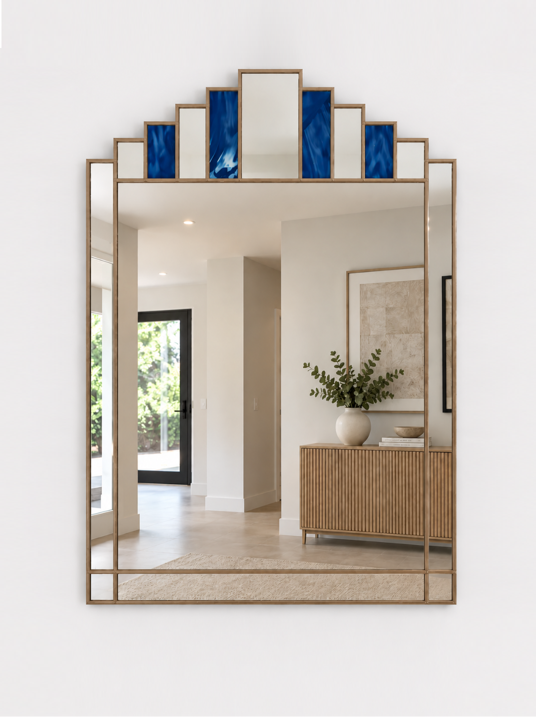 A large rectangular wall mirror with a gold metal frame and stepped top border featuring alternating blue and mirror panels