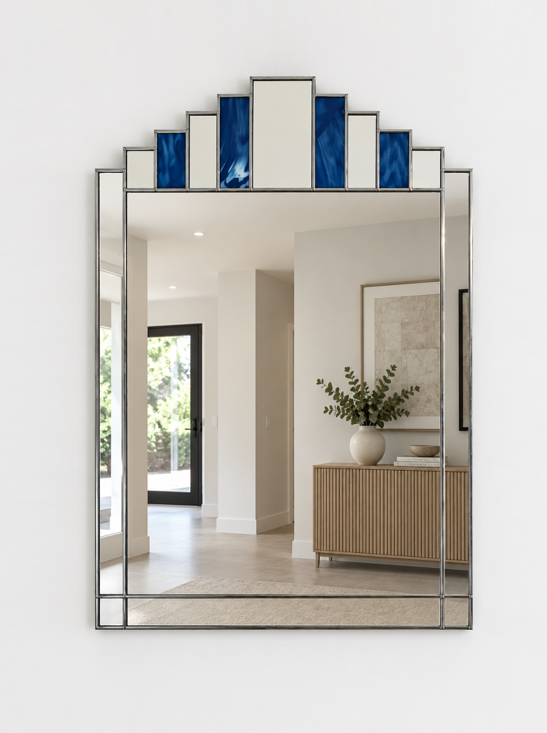 A large rectangular wall mirror with a silver metal frame and stepped top border featuring alternating blue and mirror panels