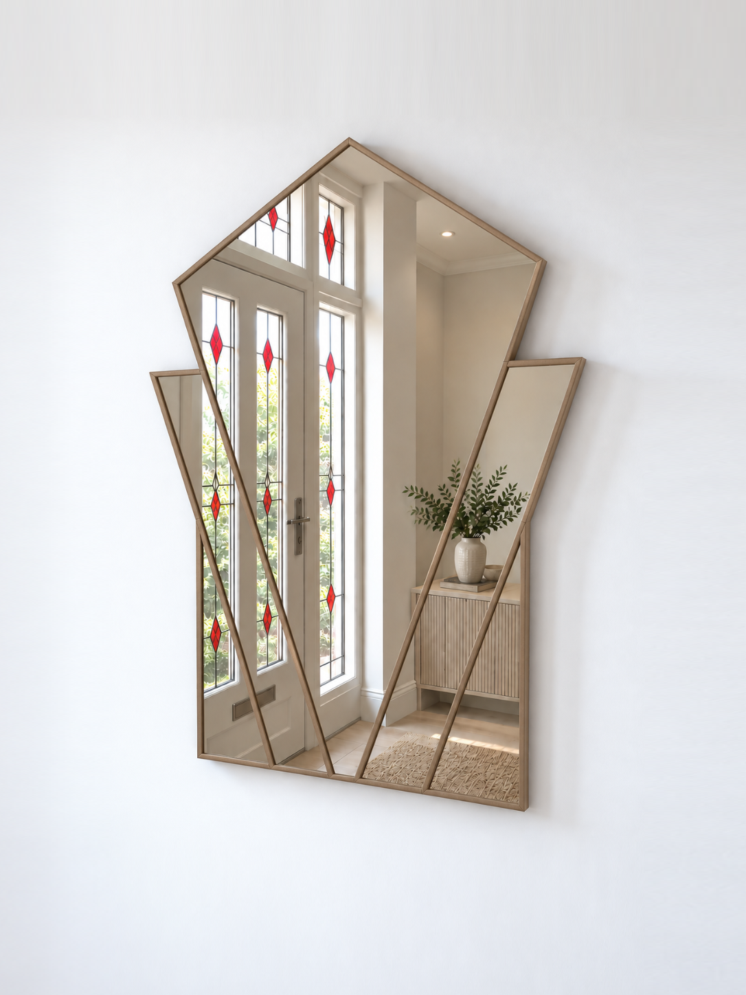 A modern geometric wall mirror with a gold frame and multiple angled panels, mounted on a white wall.