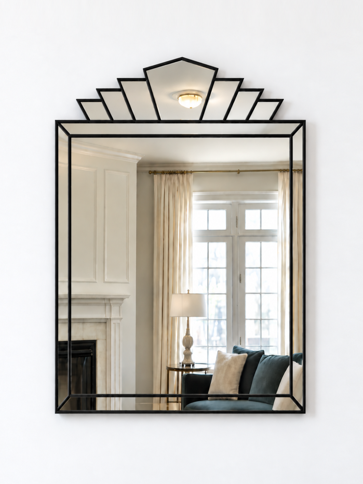 A rectangular wall mirror with a black metal frame and a decorative geometric fan-shaped top, shown mounted on a white wall.