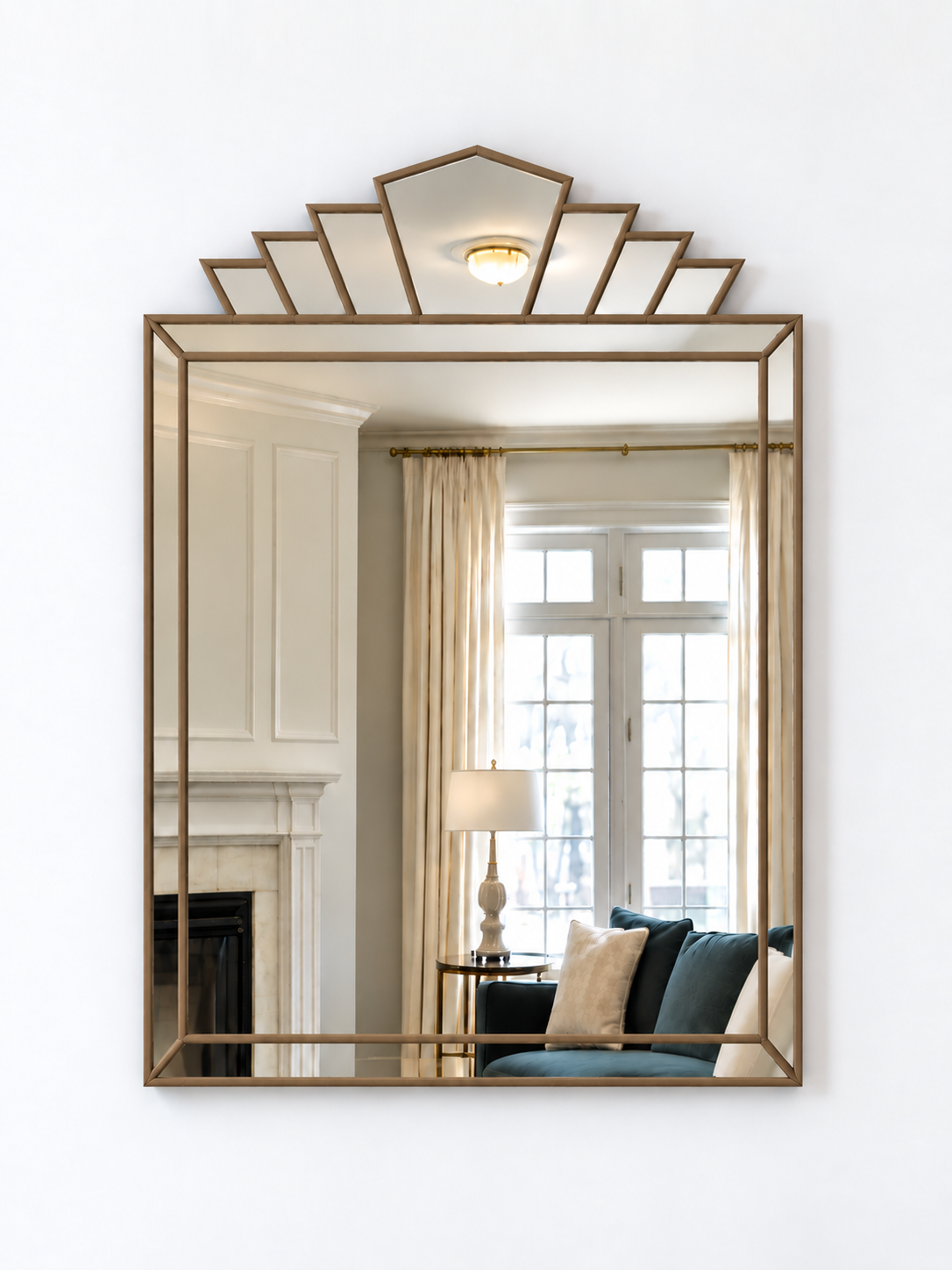 A rectangular wall mirror with a gold metal frame and a decorative geometric fan-shaped top, shown mounted on a white wall.