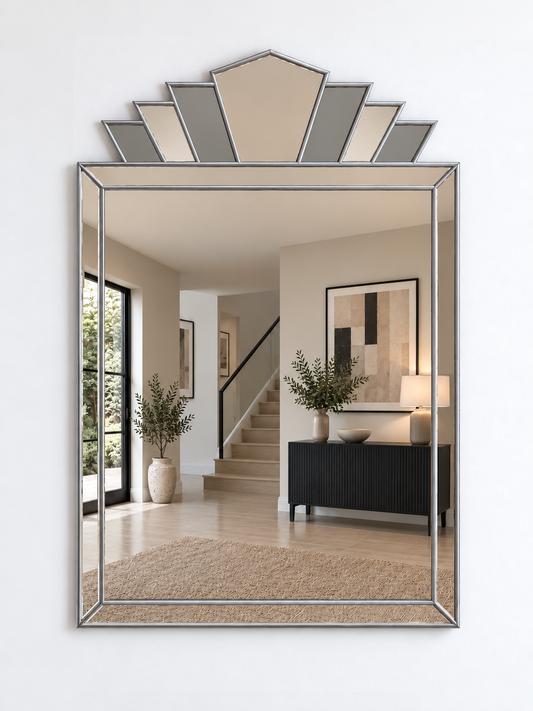 A large rectangular wall mirror with a silver-toned frame and a decorative geometric fan-shaped top