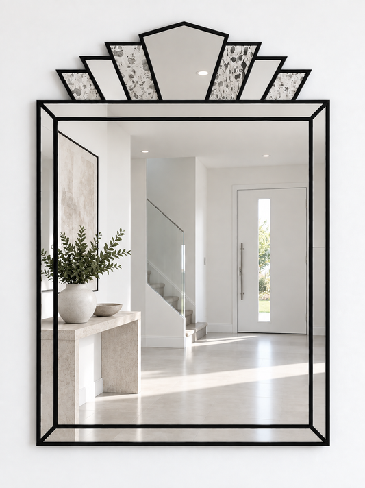 A large rectangular wall mirror with a  black metal frame and a decorative fan-shaped mirror design at the top, mounted on a white wall.