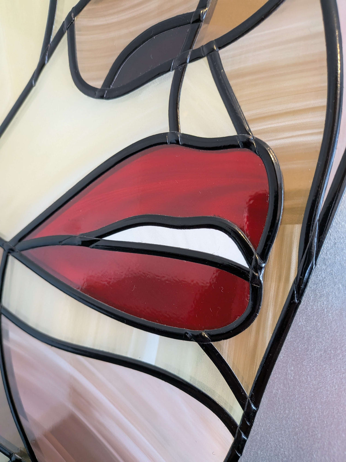 Stained glass panel with red lips design on a wooden surface